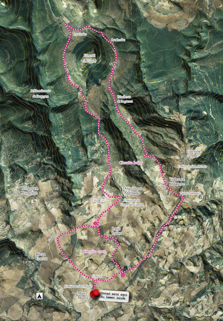 Imagen del mapa topográfico de la ruta Elimendi en BTT, dibujada con una línea rosa punteada. El punto de partida es Muez. Podemos diferenciar dos rutas, una corta y otra larga. La corta, pasa por Irujo mientras que la larga, pasa por Vidaurre, Trincheras de la Guerra, las Bordas, Pastizales… esta ruta larga rodea la cima Elimendi (1.133m) hasta unirse con la ruta corta. 